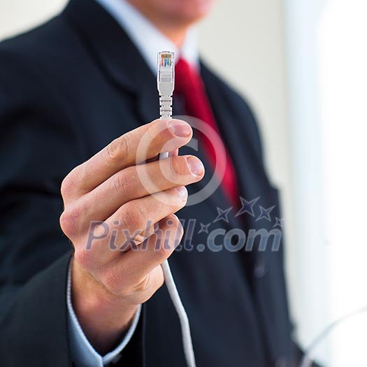 Young businessman holding an ethernet cable - stressing the importance of fast and reliable internet connection for a business (color toned image; shallow DOF)
