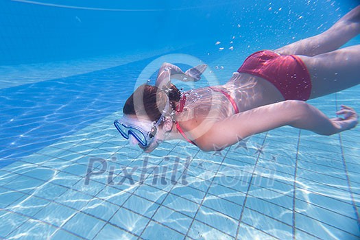 Underwater swimming: young woman swimming underwater in a pool, wearing a diving mask Underwater swimming: young woman swimming underwater in a pool, wearing a diving mask