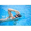 Young man swimming the front crawl in a pool