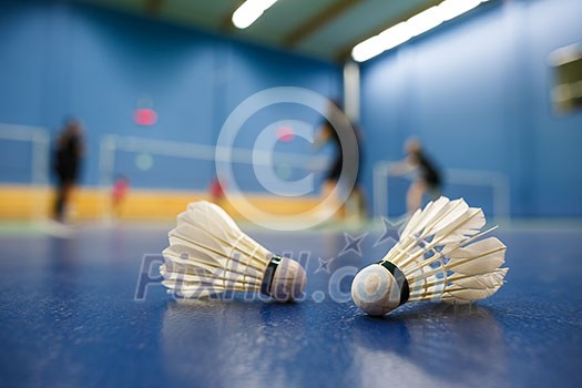 badminton - badminton courts with players competing; shuttlecocks in the foreground (shallow DOF; color toned image)