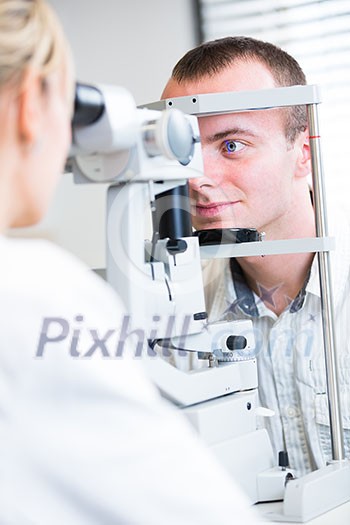 optometry concept - handsome young man having her eyes examined by an eye doctor