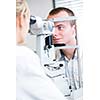 optometry concept - handsome young man having her eyes examined by an eye doctor