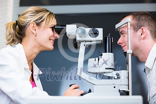 optometry concept - handsome young man having her eyes examined by an eye doctor