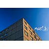 Heating in freezing winter temperatures: smoke/flue gases going out of a chimney by an apartment building against blue sky