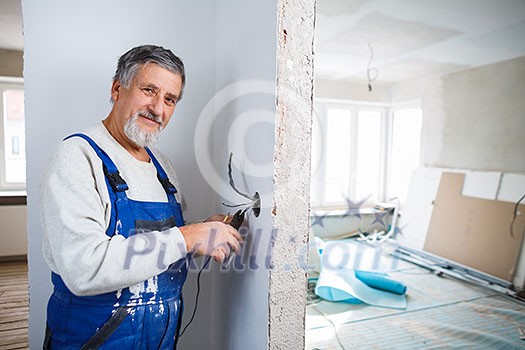 Senior man working on the electrical installations in a freshly renovated appartment