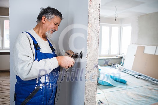 Senior man working on the electrical installations in a freshly renovated appartment