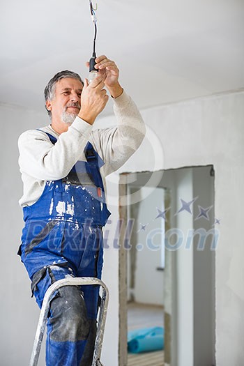 Senior man installing a bulb in a freshly renovated appartment Senior man installing a bulb in a freshly renovated appartment
