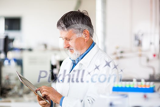 Senior doctor/scientist using his tablet computer at work (color toned image) Senior doctor/scientist using his tablet computer at work (color toned image)