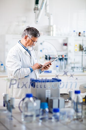 Senior doctor/scientist using his tablet computer at work (color toned image) Senior doctor/scientist using his tablet computer at work (color toned image)