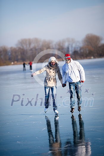 Couple ice skating outdoors on a pond on a lovely sunny winter day