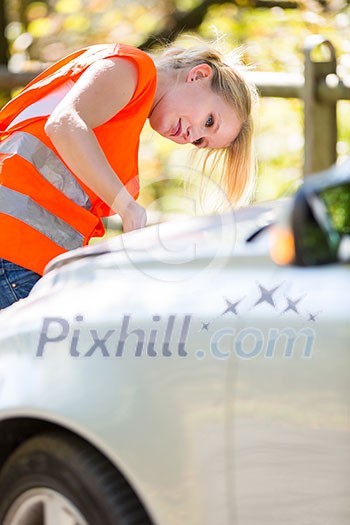 Young female driver wearing a high visibility vest on the roadside after her car has broken down Young female driver wearing a high visibility vest on the roadside after her car has broken down