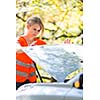 Young female driver wearing a high visibility vest on the roadside after her car has broken down