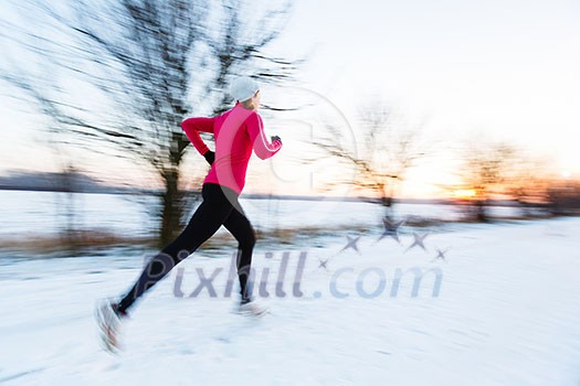 Young woman running outdoors on a cold winter day (motion blurred image)