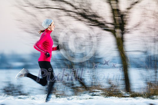 Young woman running outdoors on a cold winter day (motion blurred image)