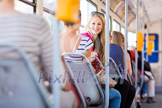 Pretty, young woman on a streetcar/tramway, during her commute to work/school (color toned image; shallow DOF)