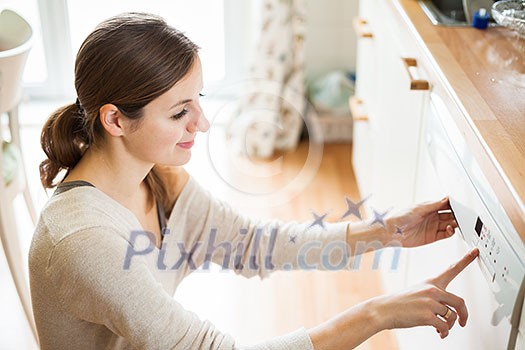 Housework: young woman putting dishes in the dishwasher