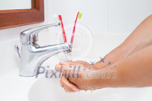 Washing hands under running water in a bathroom (shallow DOF; color toned image)