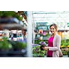 Young woman buying flowers at a garden center (color toned image; shallow DOF)