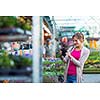 Young woman buying flowers at a garden center (color toned image; shallow DOF)