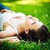Close-up portrait of an attractive young woman outdoors, lying in the grass, relaxing