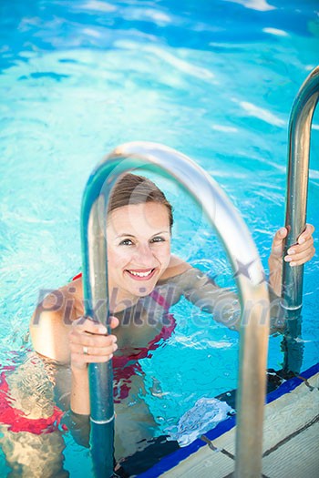Portrait of a young woman relaxing in a swimming pool (shallow DOF; color toned image)