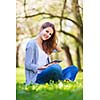 Young woman using her tablet computer while relaxing outdoors in a park on a lovely spring day