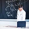 Senior chemistry professor writing on the board while having a chalk and blackboard lecture (shallow DOF; color toned image)