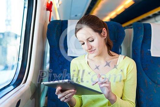 Young woman using her tablet computer while traveling by train