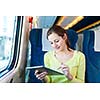 Young woman using her tablet computer while traveling by train