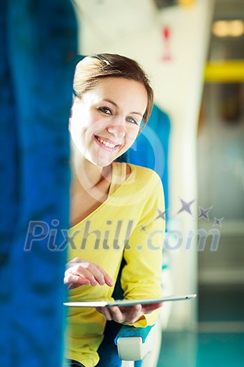 Young woman using her tablet computer while traveling by train