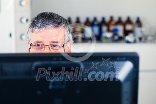 Senior researcher using a computer in the lab while working on an experiment (color toned image) Senior researcher using a computer in the lab while working on an experiment (color toned image)
