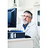 Senior researcher using a computer in the lab while working on an experiment (color toned image)