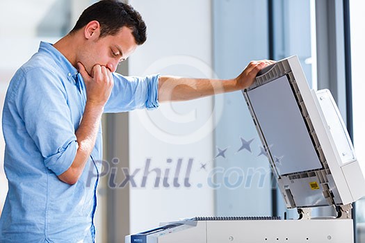 Handsome  young man using a copy machine (shallow DOF; color toned image)