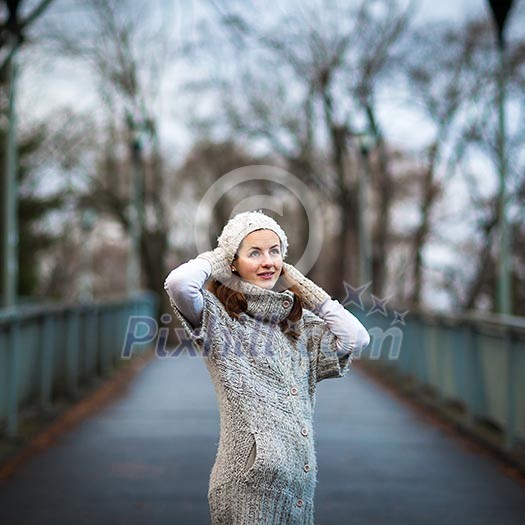 Autumn/winter portrait: young woman dressed in a warm woolen cardigan posing outside in a city park