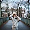 Autumn/winter portrait: young woman dressed in a warm woolen cardigan posing outside in a city park