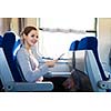 Young woman using her tablet computer while traveling by train