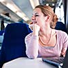 Young woman using her laptop computer while on the train (shallow DOF; color toned image)