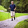 active handsome senior man nordic walking outdoors on a forest path, enjoying his retirement