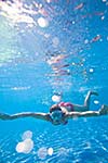 Underwater swimming: young woman swimming underwater in a pool, wearing a diving mask