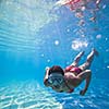 Underwater swimming: young woman swimming underwater in a pool, wearing a diving mask