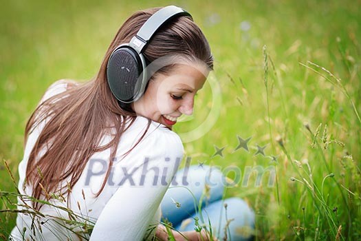 portrait of a pretty young woman listening to music on her mp3 player outdoors (daydreaming)