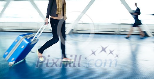 Airport rush: people with their suitcases walking along a corridor (motion blurred image; color toned image)