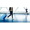 Airport rush: people with their suitcases walking along a corridor (motion blurred image; color toned image)