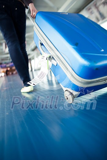 Airport rush: people with their suitcases walking along a corridor (motion blurred image; color toned image)