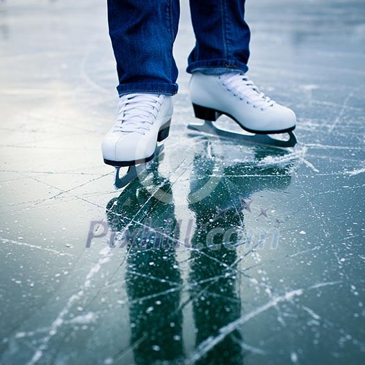 Young woman ice skating outdoors on a pond on a freezing winter day - detail of the legs Young woman ice skating outdoors on a pond on a freezing winter day - detail of the legs