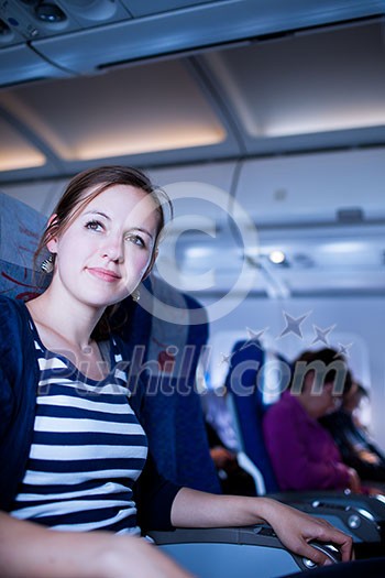 Pretty young female passenger on board of an aircraft (color toned image)