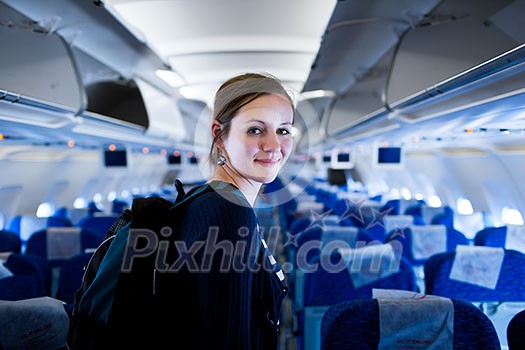 Pretty young female passenger on board of an aircraft (color toned image)