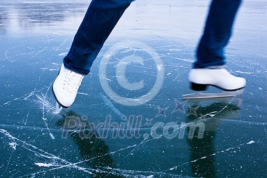 Young woman ice skating outdoors on a pond on a freezing winter day - detail of the legs