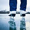 Young woman ice skating outdoors on a pond on a freezing winter day - detail of the legs