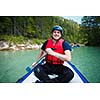 white water rafting - young man in a raft boat,  paddling, smiling